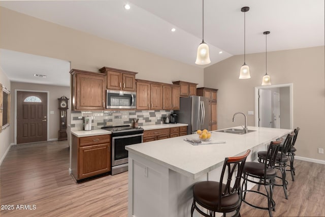 kitchen featuring stainless steel appliances, an island with sink, a sink, and light countertops