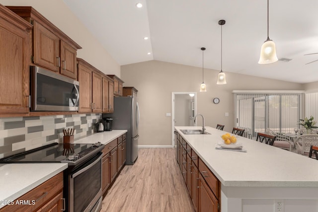 kitchen with decorative light fixtures, a center island with sink, stainless steel appliances, light countertops, and a sink