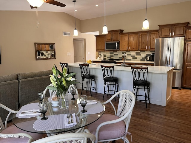 dining area with high vaulted ceiling, visible vents, dark wood finished floors, and a ceiling fan