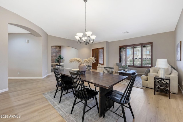 dining area featuring vaulted ceiling, a chandelier, and light hardwood / wood-style flooring