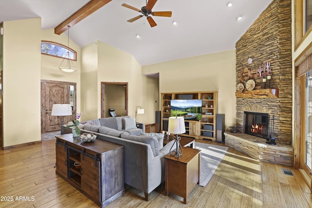 living room featuring high vaulted ceiling, a fireplace, beamed ceiling, ceiling fan, and light hardwood / wood-style flooring