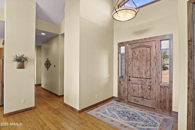 entryway featuring a high ceiling, light hardwood / wood-style floors, and a skylight