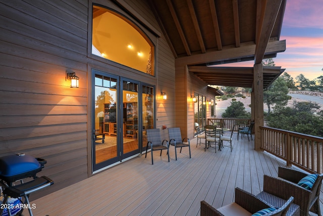 deck at dusk featuring french doors and grilling area