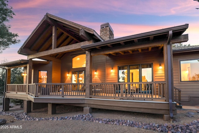 back house at dusk featuring a wooden deck