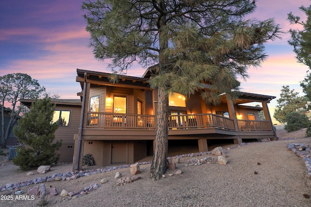 back house at dusk featuring central AC and a deck