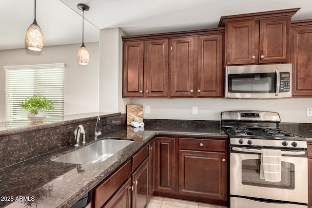 kitchen featuring stainless steel appliances, sink, dark stone counters, and decorative light fixtures