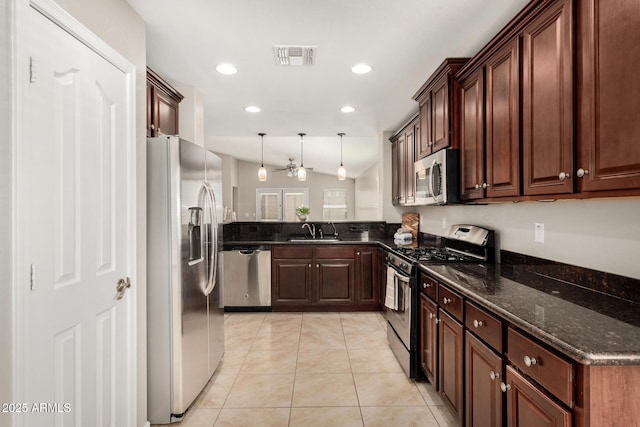 kitchen with light tile patterned flooring, vaulted ceiling, decorative light fixtures, sink, and stainless steel appliances