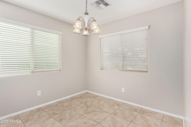 tiled empty room featuring a chandelier