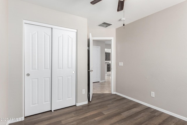 unfurnished bedroom with dark wood-type flooring, a closet, and ceiling fan