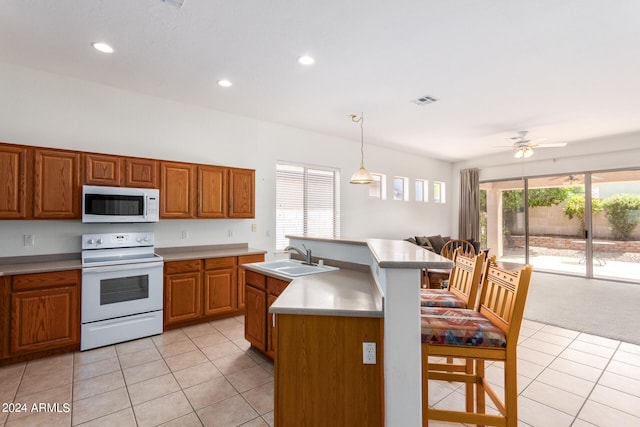 kitchen featuring white appliances, light tile patterned floors, a kitchen island with sink, ceiling fan, and sink