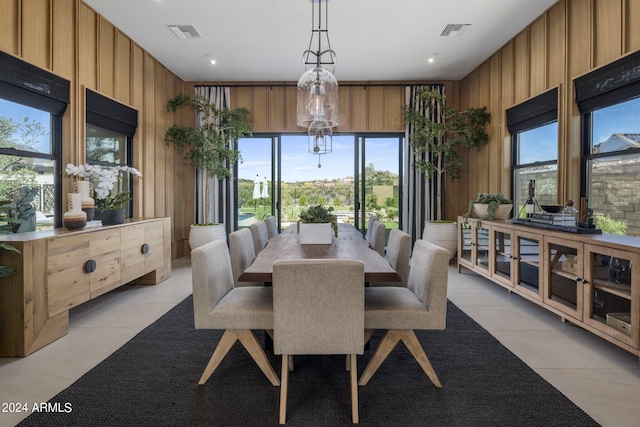 dining area with light tile patterned floors and wood walls