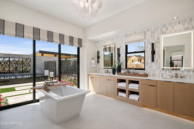 interior space with a bathing tub, vanity, tile patterned floors, and a notable chandelier