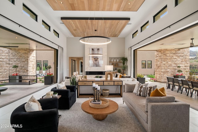 living room with ceiling fan, light tile patterned floors, wood ceiling, and a high ceiling