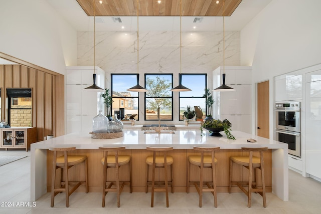 kitchen with double oven, a breakfast bar area, and a high ceiling