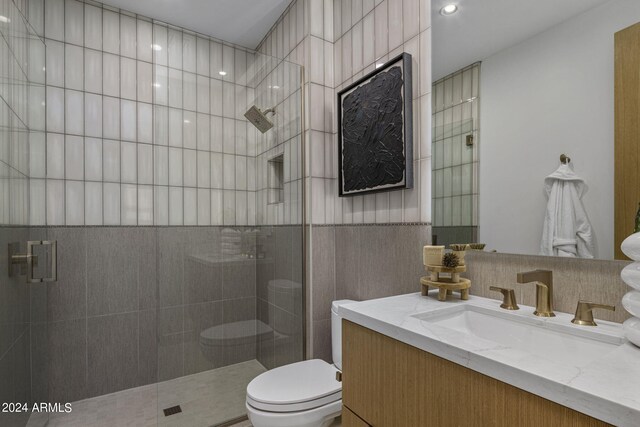 bathroom with tile walls, vanity, an enclosed shower, and toilet