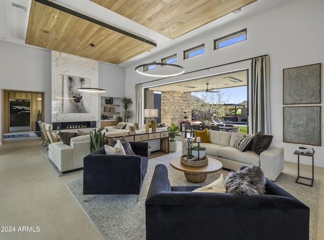 living room featuring a fireplace, a towering ceiling, and wooden ceiling