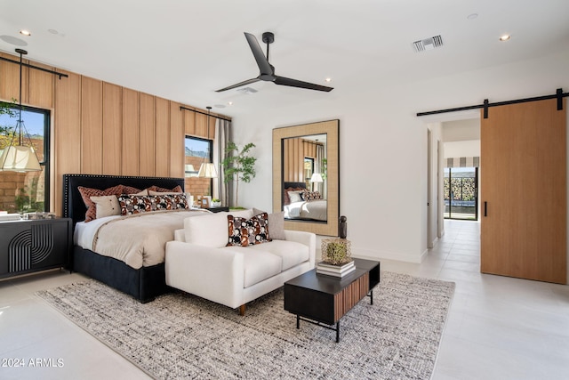 bedroom with a barn door, ceiling fan, and light tile patterned floors