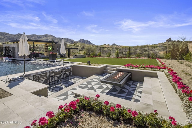 view of patio with a fire pit, a mountain view, a pool, and pool water feature