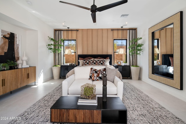 bedroom with ceiling fan, wood walls, and multiple windows