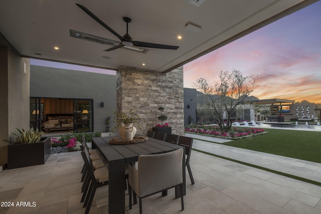 patio terrace at dusk featuring a yard and ceiling fan