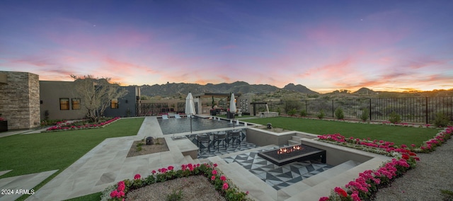 exterior space with a lawn, an outdoor fire pit, a mountain view, a patio area, and a bar