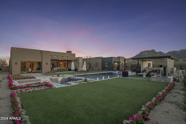 yard at dusk with area for grilling, a patio area, a fireplace, and exterior bar