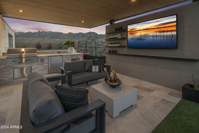 patio terrace at dusk with outdoor lounge area, a grill, and exterior kitchen