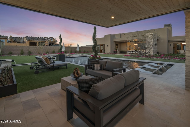 patio terrace at dusk featuring an outdoor living space and a yard