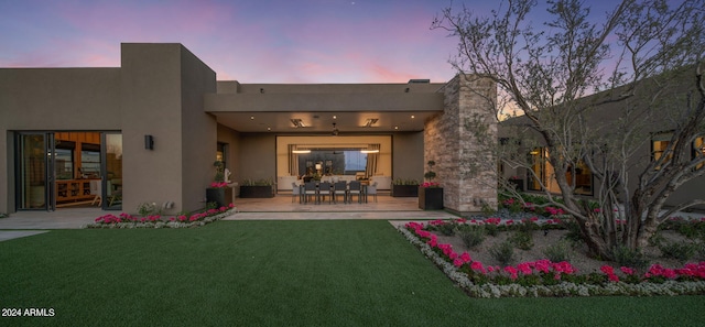 back house at dusk featuring a yard