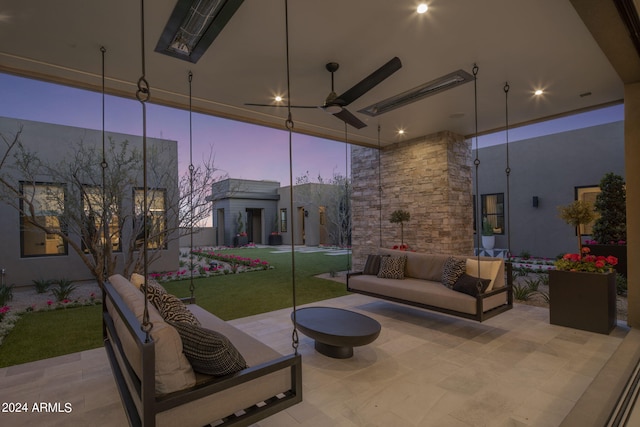 patio terrace at dusk with outdoor lounge area, ceiling fan, and a yard