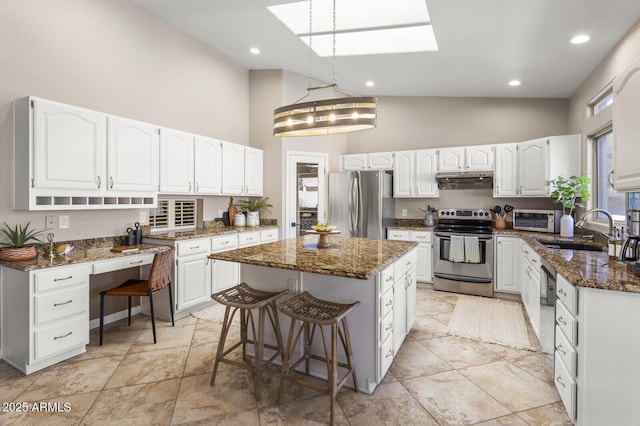 kitchen featuring sink, white cabinetry, dark stone countertops, stainless steel appliances, and a kitchen island