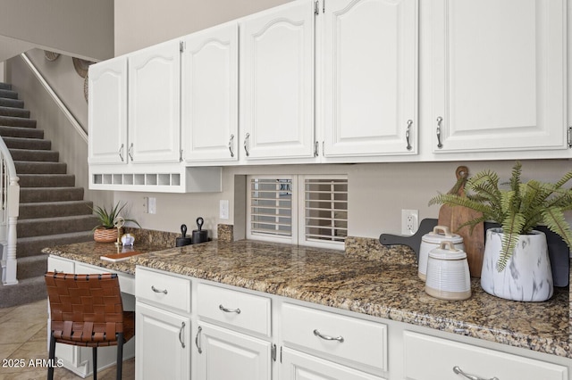 kitchen with white cabinets, tile patterned floors, and dark stone counters