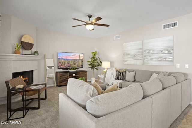 carpeted living room featuring a fireplace and ceiling fan