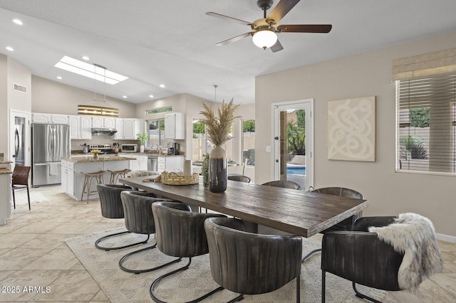 dining space with lofted ceiling with skylight and ceiling fan