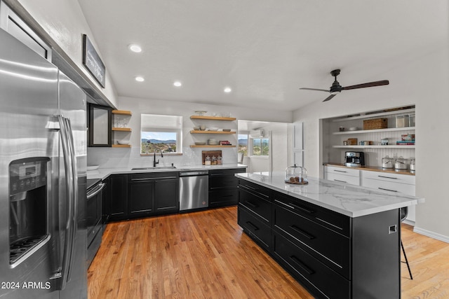 kitchen with sink, light hardwood / wood-style flooring, stainless steel appliances, a kitchen breakfast bar, and a center island