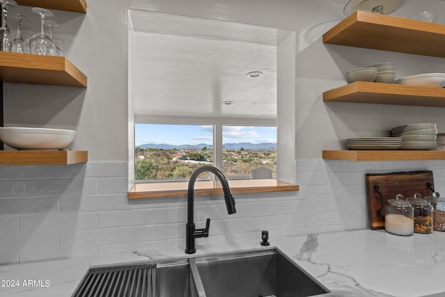 kitchen with a mountain view, light stone countertops, sink, and decorative backsplash