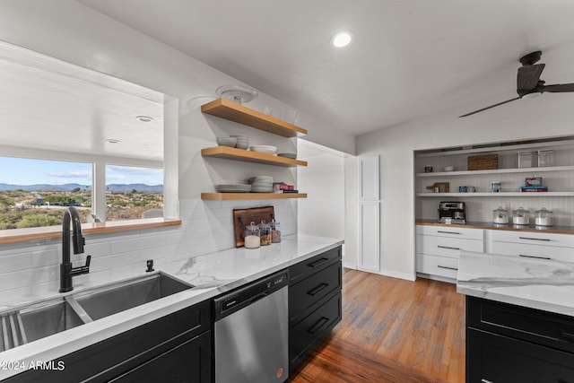 kitchen featuring light hardwood / wood-style floors, vaulted ceiling, light stone countertops, dishwasher, and sink