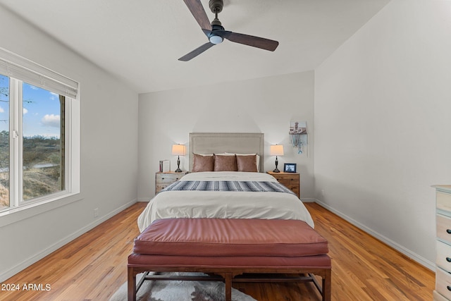 bedroom with light hardwood / wood-style floors, vaulted ceiling, and ceiling fan