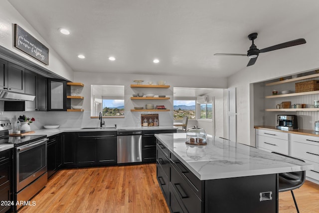 kitchen with a breakfast bar, light wood-type flooring, sink, a kitchen island, and appliances with stainless steel finishes