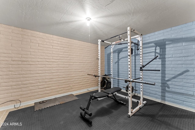 workout area featuring a textured ceiling and brick wall