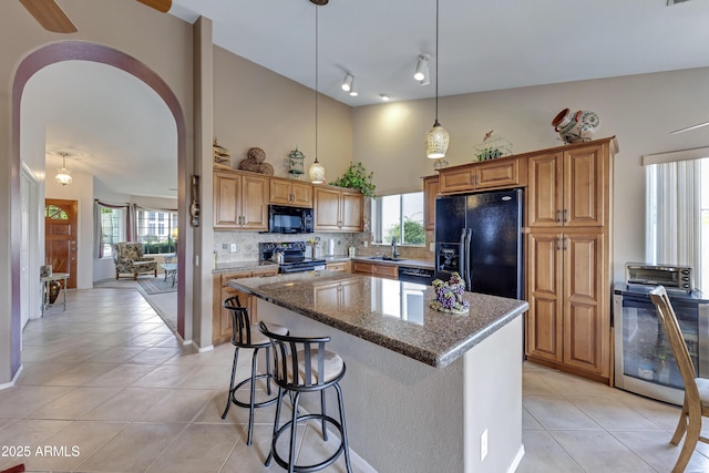 16230 E Glenpoint Dr, Fountain Hills, AZ 85268 - kitchen with a center island, light tile patterned floors, dark stone countertops, backsplash, and black appliances