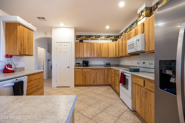 kitchen featuring washer / dryer, white appliances, and light tile patterned floors