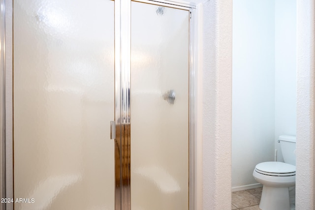 bathroom featuring tile patterned flooring, walk in shower, and toilet