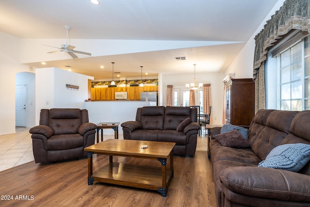 living room with hardwood / wood-style flooring, ceiling fan with notable chandelier, lofted ceiling, and a wealth of natural light