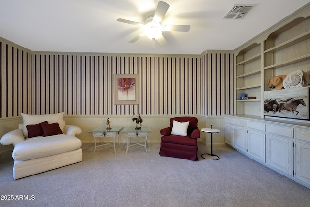 living area featuring light carpet, built in features, and ceiling fan