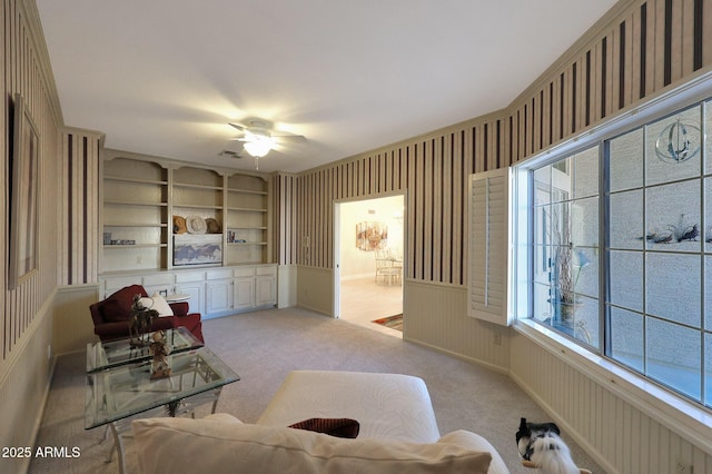 carpeted living room with ceiling fan and built in features