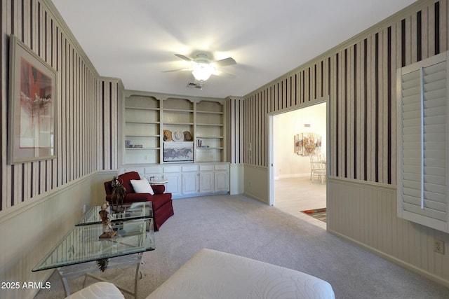 carpeted living room featuring built in shelves and ceiling fan