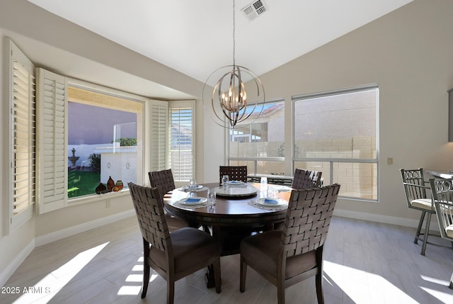 dining room featuring light hardwood / wood-style floors, lofted ceiling, and an inviting chandelier