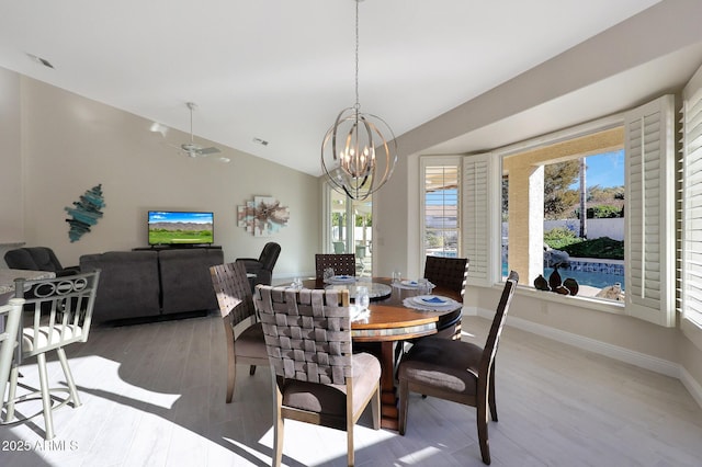 dining room featuring ceiling fan with notable chandelier, light wood-type flooring, and vaulted ceiling