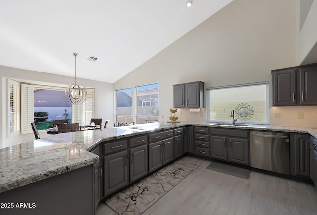 kitchen with sink, stainless steel dishwasher, a notable chandelier, light hardwood / wood-style floors, and light stone counters